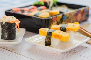 sushi tamagoyaki ou ovo doce no envoltório de arroz e algas no prato quadrado branco. deliciosa comida japonesa.