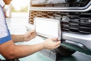 técnico mudando o número da placa do carro no centro de serviço foto