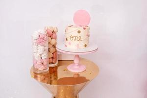 lindo bolo de aniversário com decoração rosa para o aniversário de uma criança de um ano. barra de chocolate com macaroons e marshmallows foto