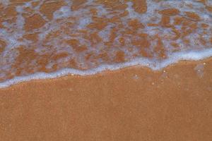 ondas em uma praia de areia ao pôr do sol foto