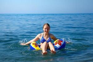 garota feliz nada no mar em um círculo foto
