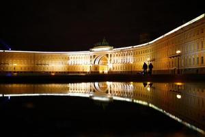 reflexão em um edifício iluminado poça em st. petersburgo na praça do palácio foto