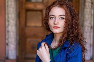 retrato de mulher bonita com cabelo vermelho na capa azul posando na câmera foto