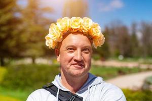 alegre retrato de um homem careca com uma coroa de flores na cabeça em um dia ensolarado foto