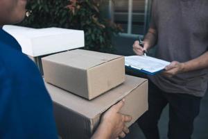 entrega jovem parado na porta de casa e carregando pacotes para o jovem macho para assinar. foto