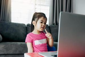 menina asiática participando da aula de plataforma de e-learning on-line em casa enquanto a escola foi fechada durante o surto de coronavírus. foto