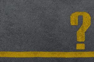 sinal de interrogação amarelo pintado em uma superfície de estrada de asfalto foto