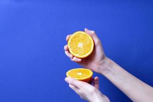 mão de uma mulher segurando uma laranja madura cortada foto