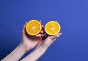 mão de uma mulher segurando uma laranja madura cortada foto