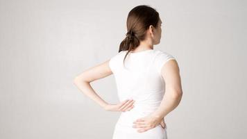 atraente adolescente sofre de dor nas costas. tudo em fundo branco foto