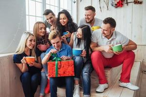 grupo de melhores amigos na festa. pessoas sorridentes e alegres sentadas nas escadas uma xícara de café cumprimentam o aniversário, grande presente foto