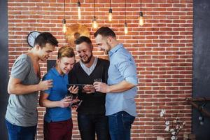 alegres velhos amigos se comunicam e observam o telefone, copos de uísque no pub. estilo de vida de entretenimento de conceito. pessoas conectadas por wifi em reunião de mesa de bar foto