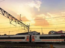 um trem cruzando os trilhos sob o céu crepuscular foto