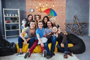 retrato de grupo de meninos e meninas multiétnicas com roupas coloridas da moda segurando amigo posando em uma parede de tijolos, pessoas de estilo urbano se divertindo, conceitos sobre estilo de vida de união juvenil foto