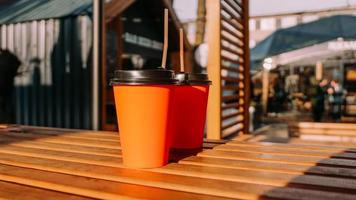 xícaras de café de papel laranja para levar na mesa de madeira. foto