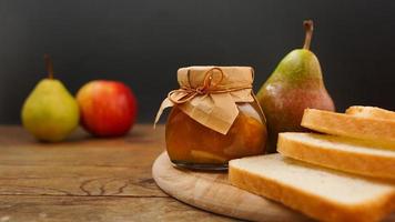 frasco de vidro de geléia caseira de pêra e maçã com frutas frescas em cima da mesa foto