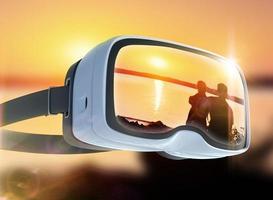 fone de ouvido de realidade virtual, dupla exposição, casal romântico na praia ao fundo colorido por do sol foto