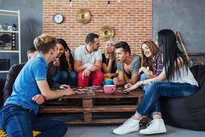 grupo de amigos criativos sentados à mesa de madeira. pessoas se divertindo jogando jogo de tabuleiro foto