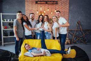 retrato de grupo de meninos e meninas multiétnicas com roupas coloridas da moda segurando amigo posando em uma parede de tijolos, pessoas de estilo urbano se divertindo, conceitos sobre estilo de vida de união juvenil foto