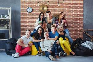 retrato de grupo de meninos e meninas multiétnicas com roupas coloridas da moda segurando amigo posando em uma parede de tijolos, pessoas de estilo urbano se divertindo, conceitos sobre estilo de vida de união juvenil foto