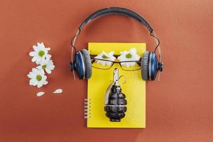 notebook, fones de ouvido e granada de guerra em um fundo de madeira marrom foto