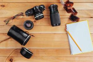 a velha câmera de filme e rolo de filme e caderno com lápis em um fundo de madeira foto