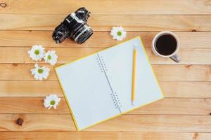 no lápis de caderno de fundo de madeira, café e flores. foto