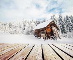 paisagem de montanhas de inverno com uma floresta de neve e cabana de madeira foto