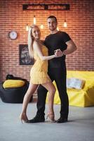 jovem casal dançando música latina bachata, merengue, salsa. duas poses de elegância no café com paredes de tijolos foto