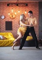 jovem casal dançando música latina. bachata, merengue, salsa. duas poses de elegância no café com paredes de tijolos foto