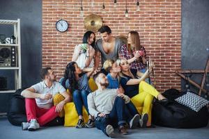 retrato de grupo de meninos e meninas multiétnicas com roupas coloridas da moda segurando amigo posando em uma parede de tijolos, pessoas de estilo urbano se divertindo, conceitos sobre estilo de vida de união juvenil foto