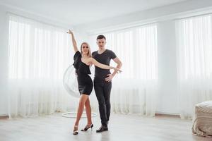 jovem casal dançando música latina. bachata, merengue, salsa. duas pose de elegância no quarto branco foto