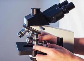 close-up de mãos de cientista com microscópio, examinando amostras. foto