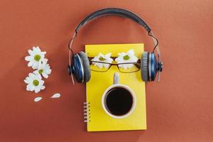 notebook, fones de ouvido e café em um fundo de madeira marrom foto