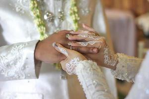 a noiva coloca um anel de casamento no dedo do noivo foto