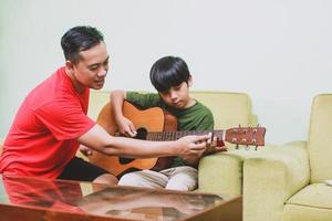 pai ensinando violão para seu filho em casa foto