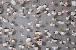decoração de casamento com muitas flores artificiais penduradas na parede cinza. foto