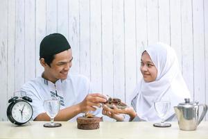jovem casal muçulmano na hora do iftar. mulher muçulmana dando datas para homem muçulmano. ramadã tradicional, refeição iftar. conceito de mês de jejum ramadan kareem foto