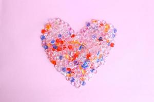 forma de coração colorido de bolinhas de gude no fundo rosa foto