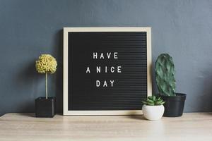 tenha uma citação de bom dia no quadro-negro com cactos, plantas suculentas e decorativas na mesa de madeira foto
