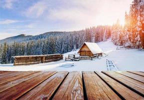 paisagem de montanhas de inverno com uma floresta de neve e cabana de madeira foto