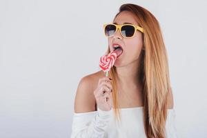 retrato de jovem sorridente com pirulito em forma de coração e óculos de sol foto