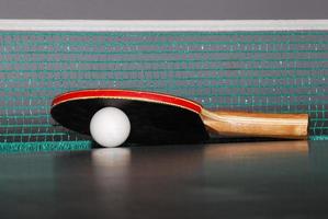 raquete de tênis de mesa com close-up de bola e rede foto