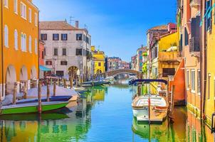 paisagem urbana de chioggia com canal de água estreito vena com barcos multicoloridos ancorados entre antigos edifícios coloridos foto