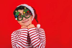 feliz natal. criança sorridente usando chapéu de papai noel e óculos de natal engraçados foto