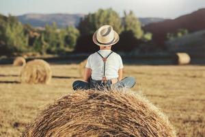 menino pensativo no campo de palha foto