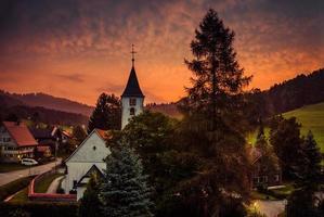 pequena aldeia bolsternang com igreja, sul da alemanha, ao pôr do sol foto