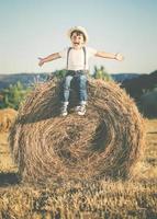 criança feliz brincando no campo de trigo foto