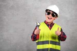 trabalhador da construção civil de capacete branco e óculos de sol e segurando uma chave inglesa foto