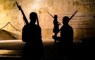 figura silhueta de guardas evzones à noite em frente ao monumento do soldado desconhecido foto